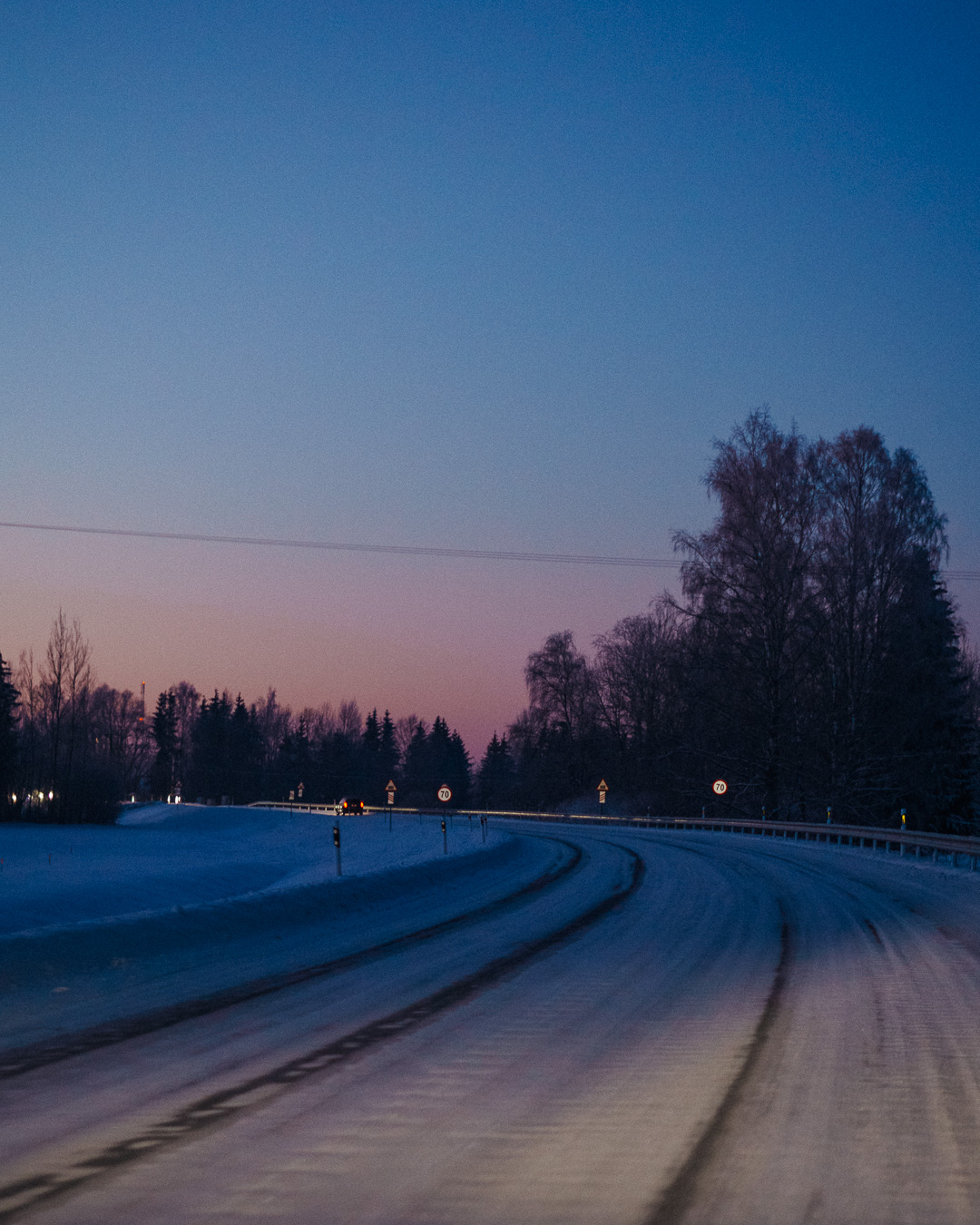 Dark snowy road with a sunset in the background