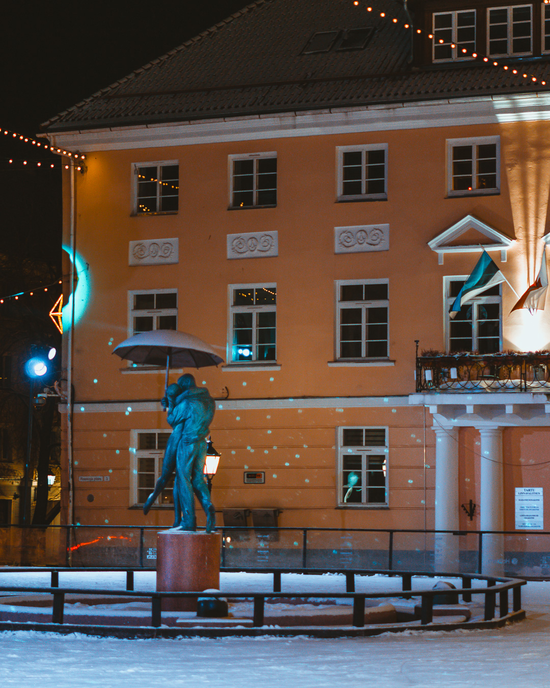 Tartu town hall behind a statue of a man and woman under an umbrella